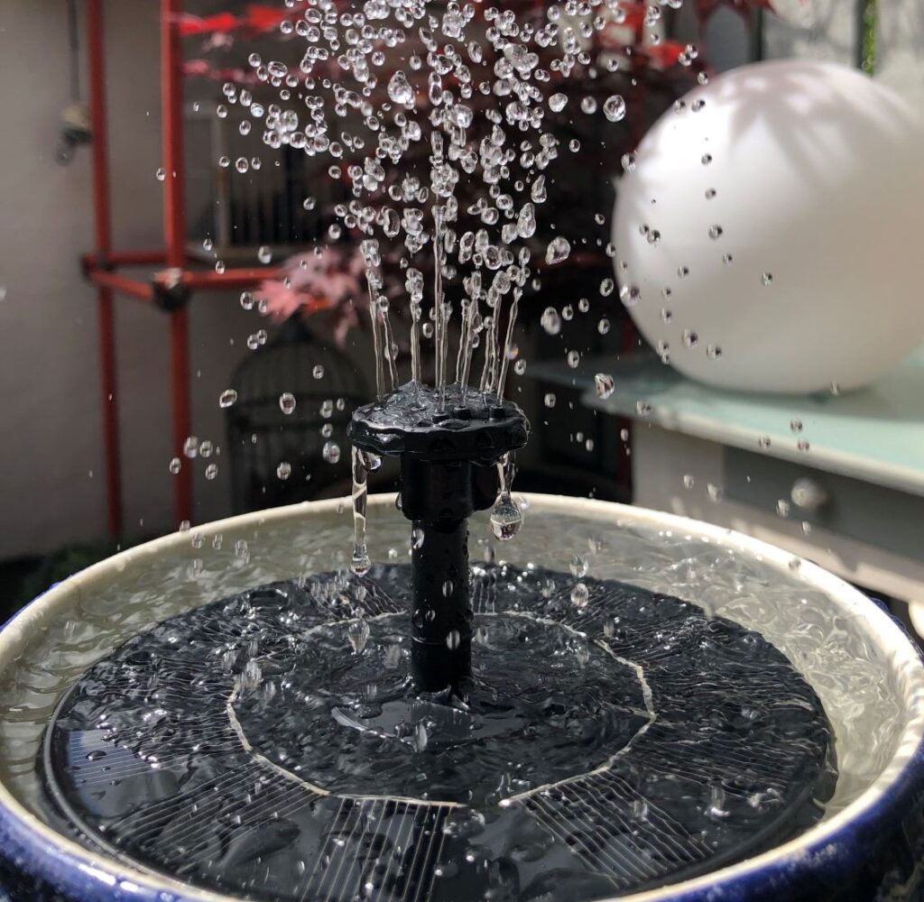 Solar fountain in a birdbath with adjustable spray.